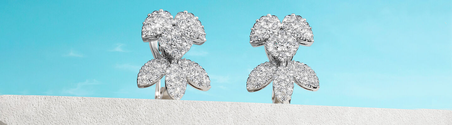 Birks Snowflake snow angel earrings on a blue background.